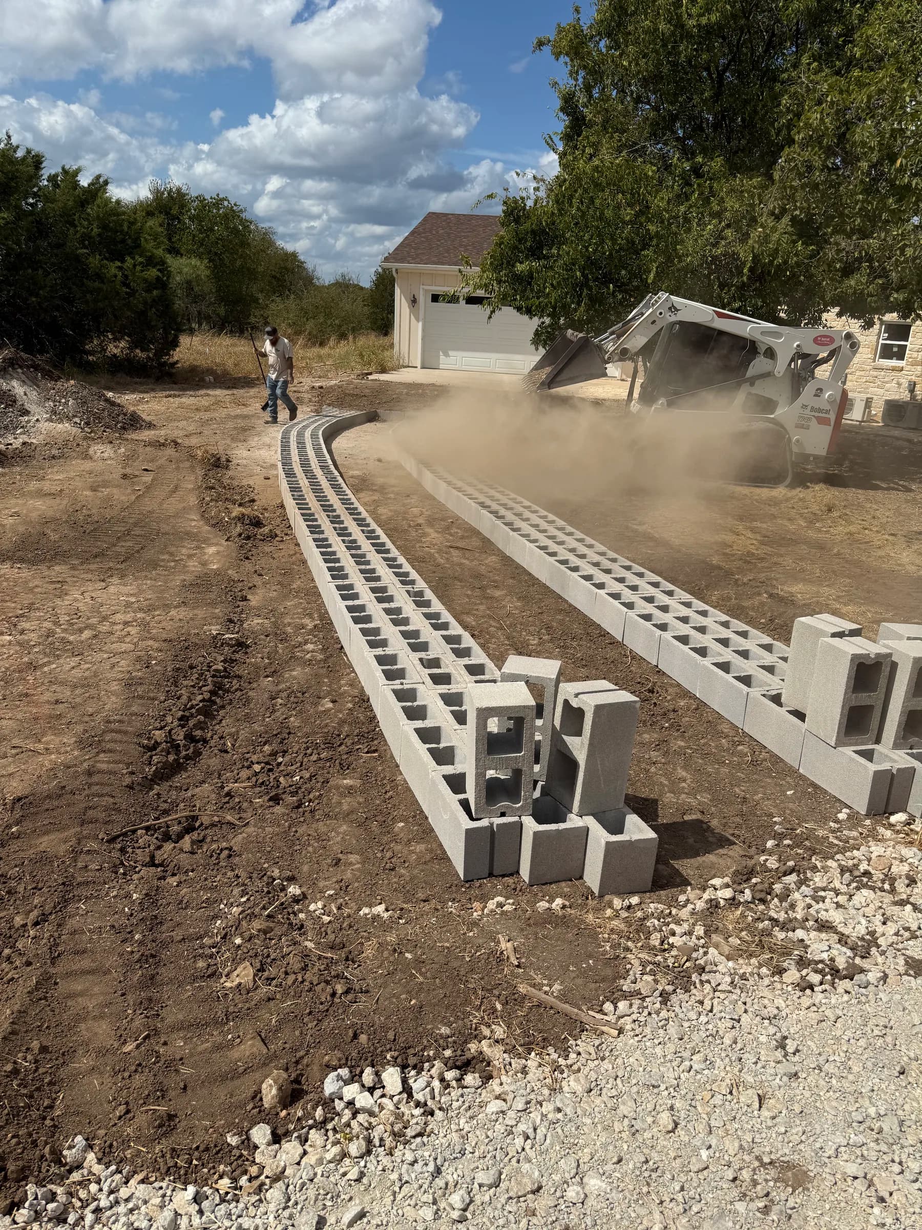 Crew and skid steer working beside the curved concrete driveway blocks at White Hall