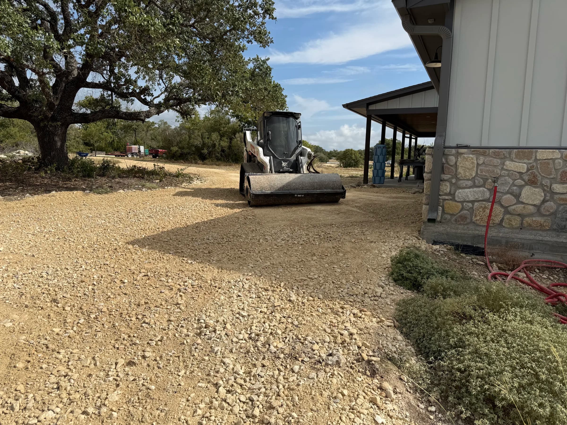 A Bobcat roller compacting aggregate alongside the Ding Dong home