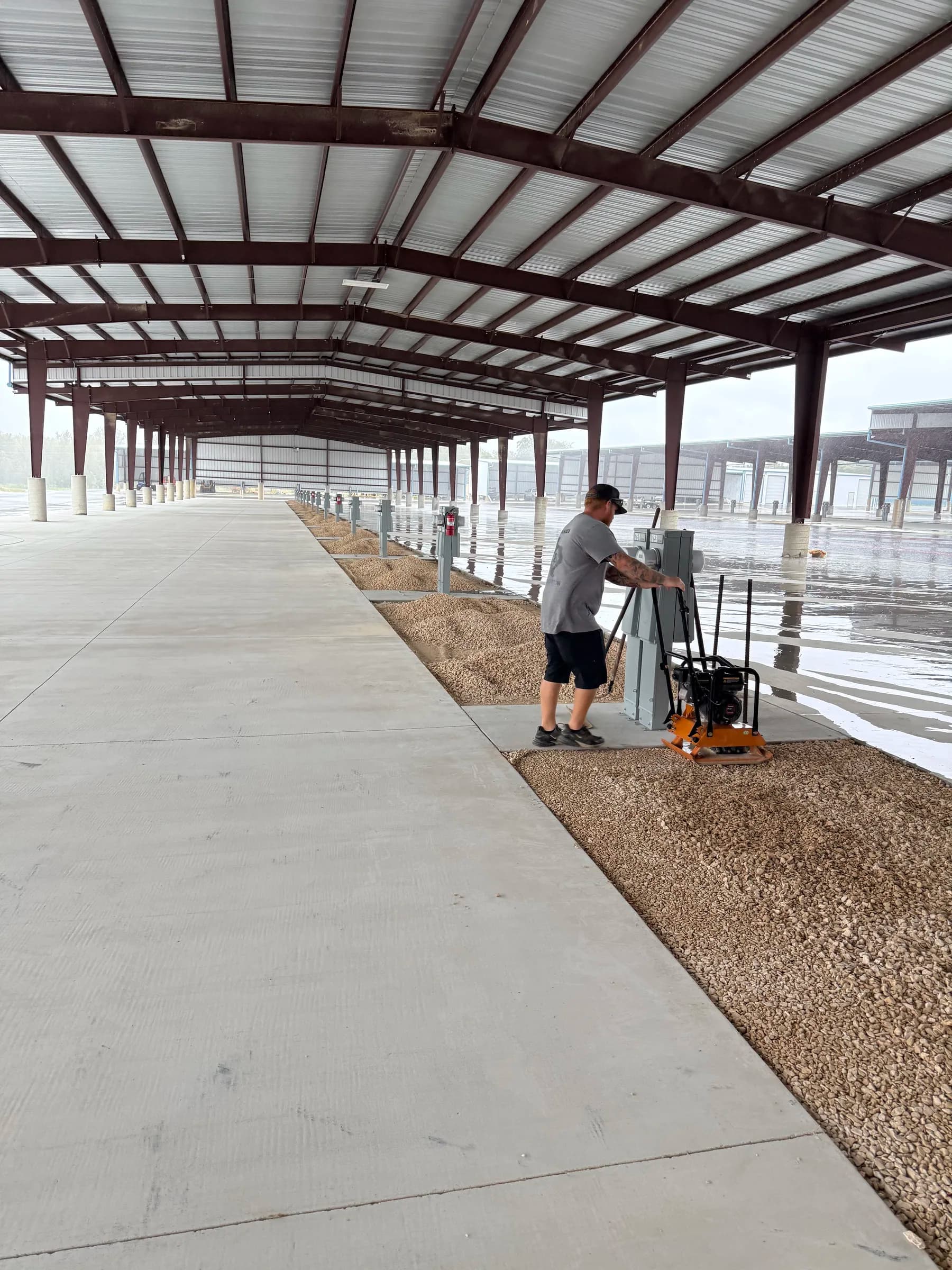 Crew member compacting gravel around electrical pedestals at a Killeen RV storage property