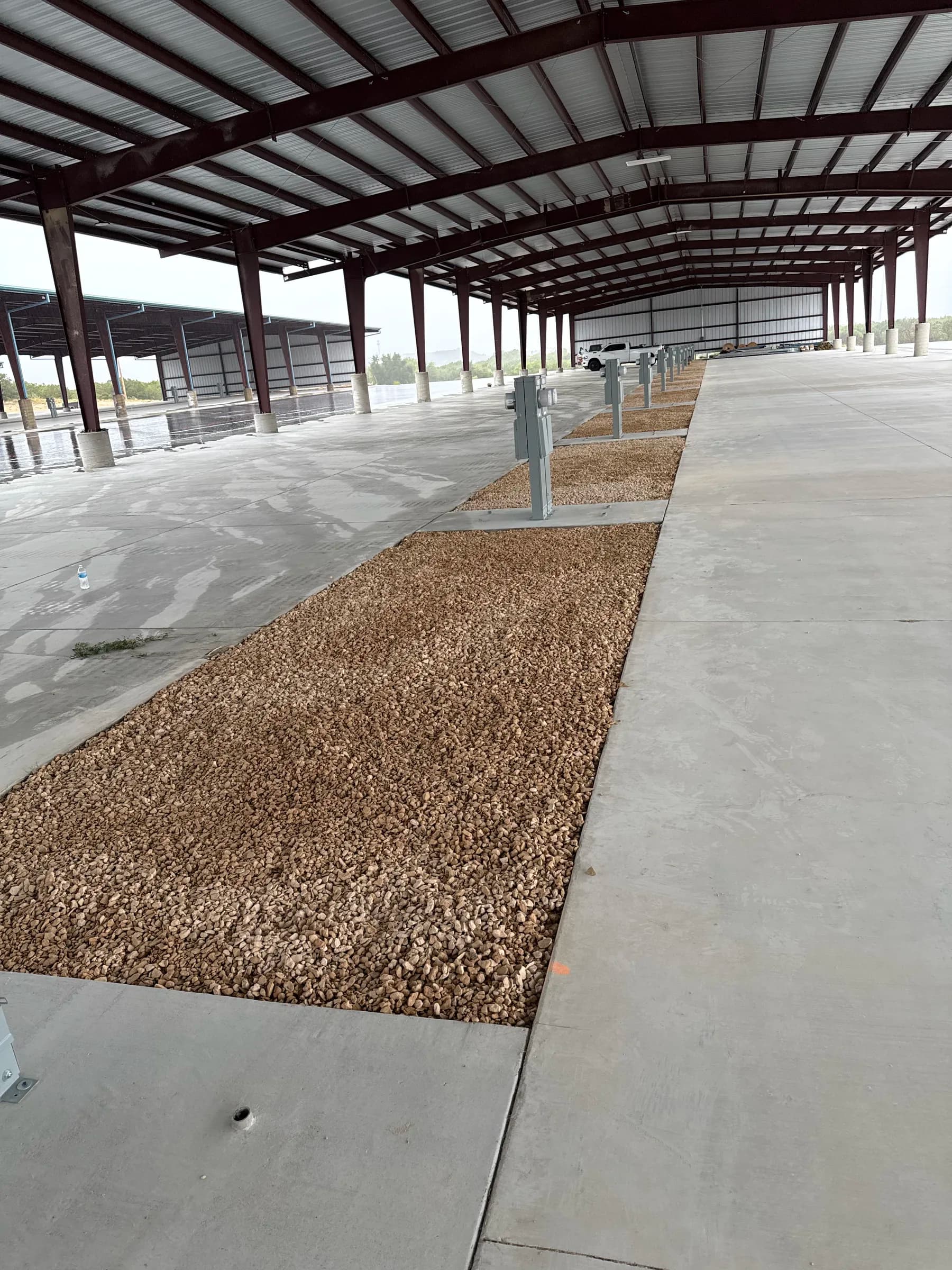 Placed gravel between concrete parking areas beneath the existing RV storage canopy