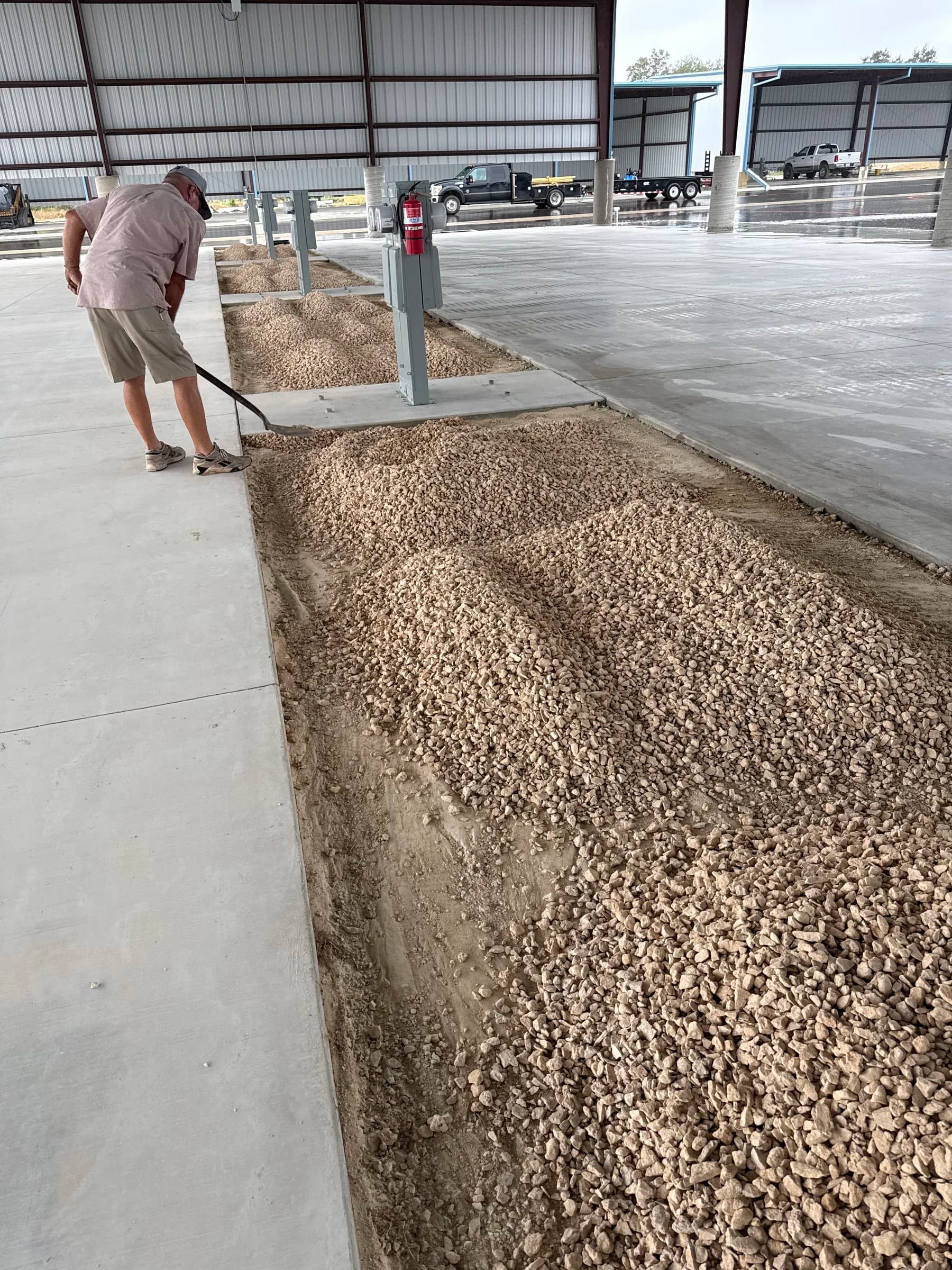 Crew member raking gravel between the concrete RV parking bays in Killeen